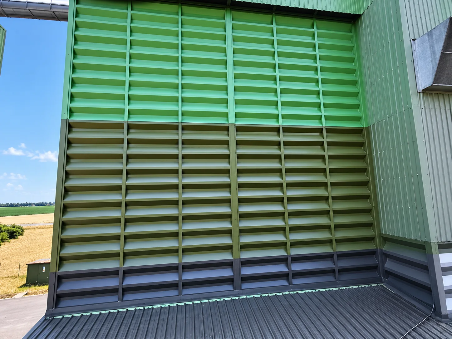 Détail frontal d’un bardage nervuré peint en bandes horizontales, soubassement anthracite.