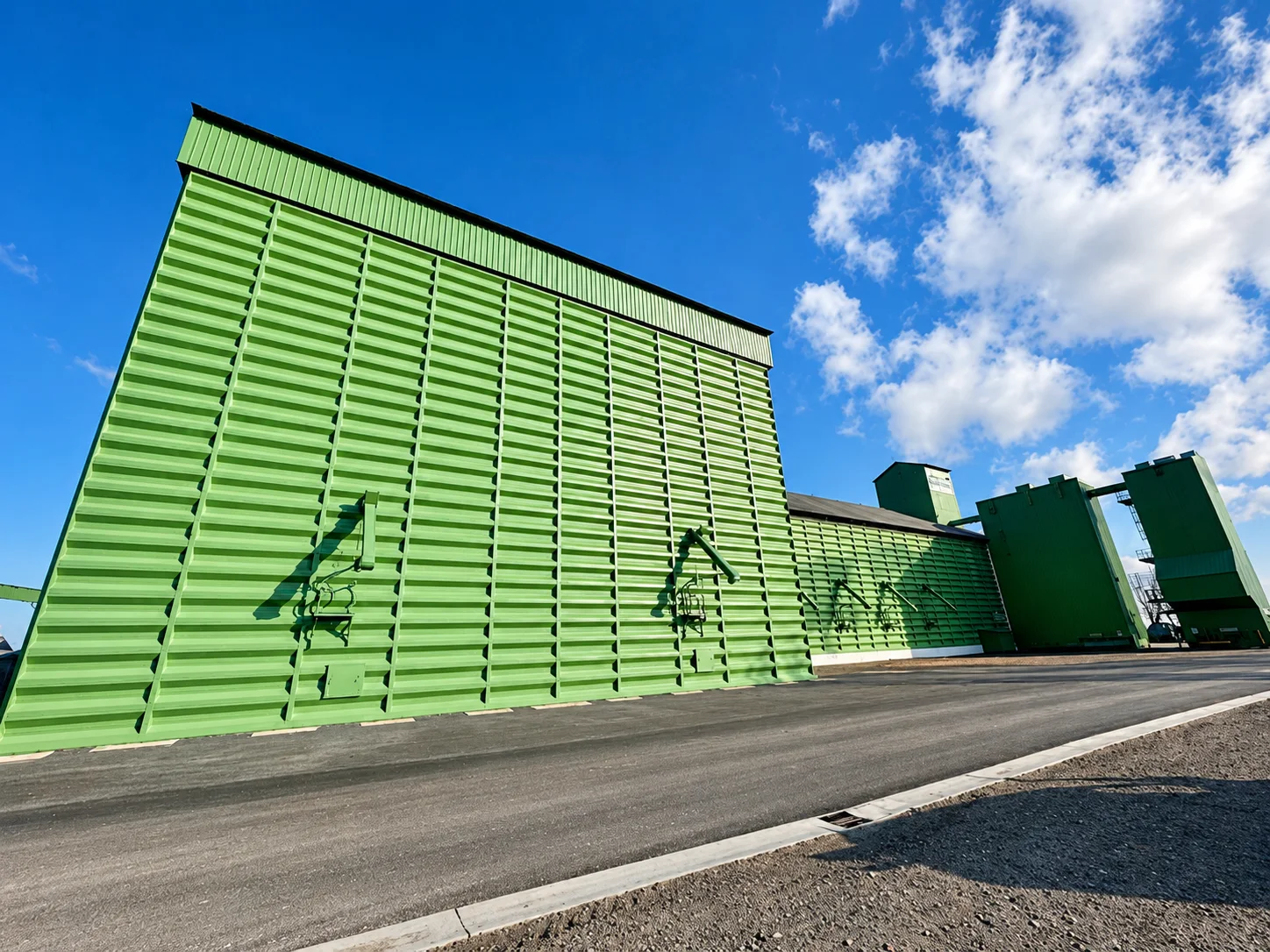 Grand pignon peint en vert pomme, nervures horizontales, route au premier plan.
