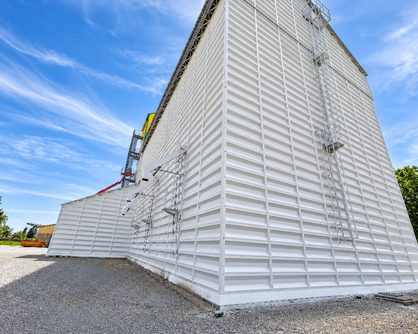 Cellule de stockage en bardage blanc, arête vive, vue en contre-plongée.